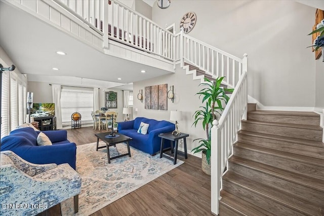 living area featuring dark wood-style floors, recessed lighting, a high ceiling, baseboards, and stairs