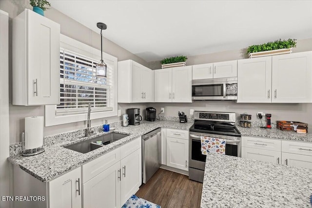 kitchen with dark wood-style floors, pendant lighting, appliances with stainless steel finishes, white cabinetry, and a sink