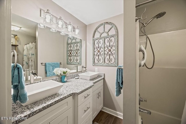 bathroom featuring double vanity, baseboards, a sink, and wood finished floors