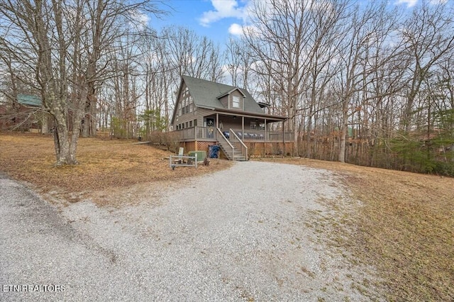 chalet / cabin featuring covered porch, driveway, and stairway