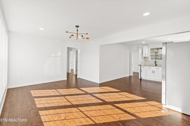 unfurnished living room featuring baseboards, dark wood-type flooring, and recessed lighting