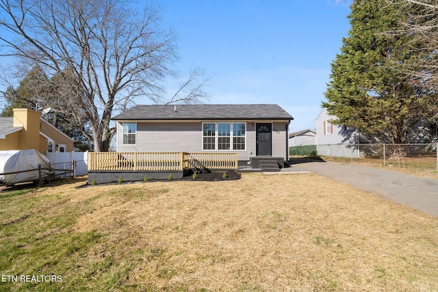 back of house with a wooden deck, fence, and a yard