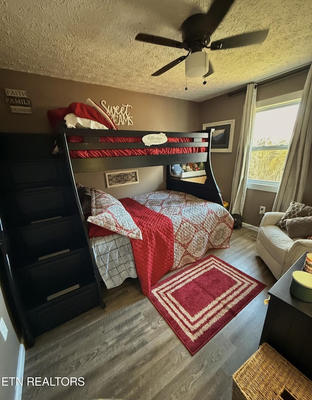 bedroom featuring ceiling fan, wood finished floors, baseboards, and a textured ceiling