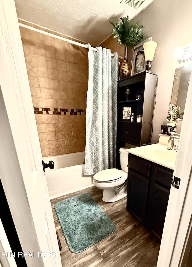 bathroom with visible vents, toilet, wood finished floors, shower / tub combo, and vanity