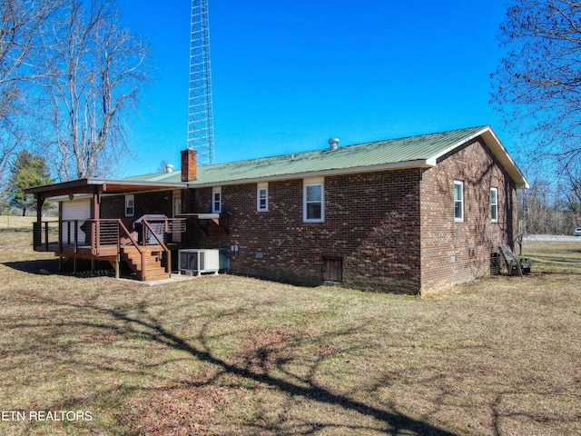 back of property featuring a lawn, a chimney, metal roof, a wooden deck, and brick siding