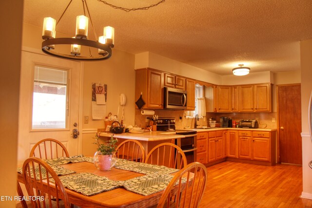 dining area with a textured ceiling, light wood-style flooring, and a notable chandelier