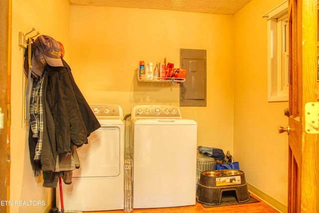 laundry area featuring a textured ceiling, laundry area, wood finished floors, electric panel, and washing machine and clothes dryer