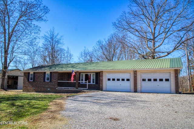 view of front facade with metal roof, an attached garage, brick siding, crawl space, and gravel driveway