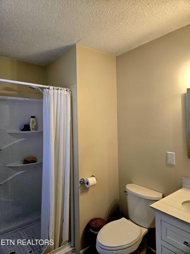 bathroom with a stall shower, vanity, toilet, and a textured ceiling