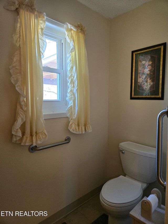 bathroom featuring tile patterned flooring, baseboards, and toilet