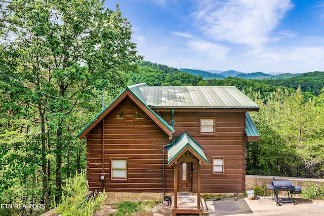 view of front of home featuring metal roof, a forest view, and a mountain view