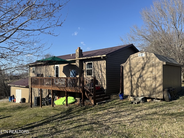 rear view of house featuring a storage shed, a deck, a lawn, and an outbuilding