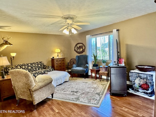 living room with a textured ceiling, a ceiling fan, and wood finished floors