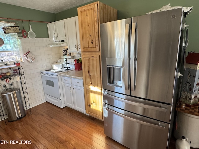 kitchen with white electric stove, light countertops, light wood-style floors, white cabinets, and stainless steel fridge