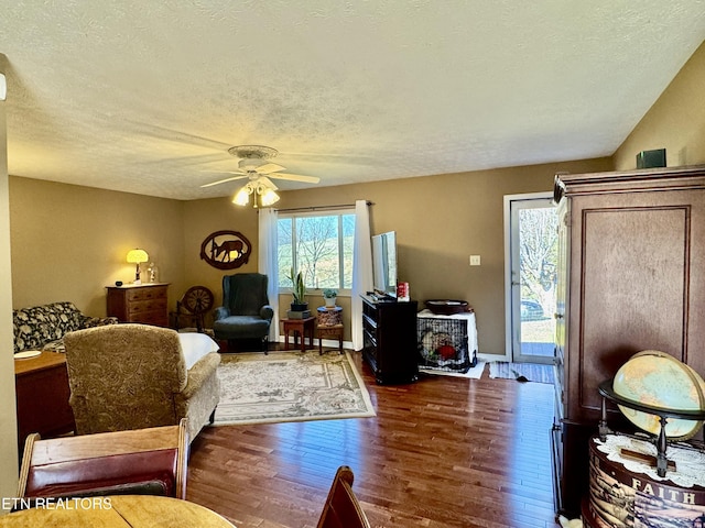 living room featuring a textured ceiling, ceiling fan, and dark wood-style flooring