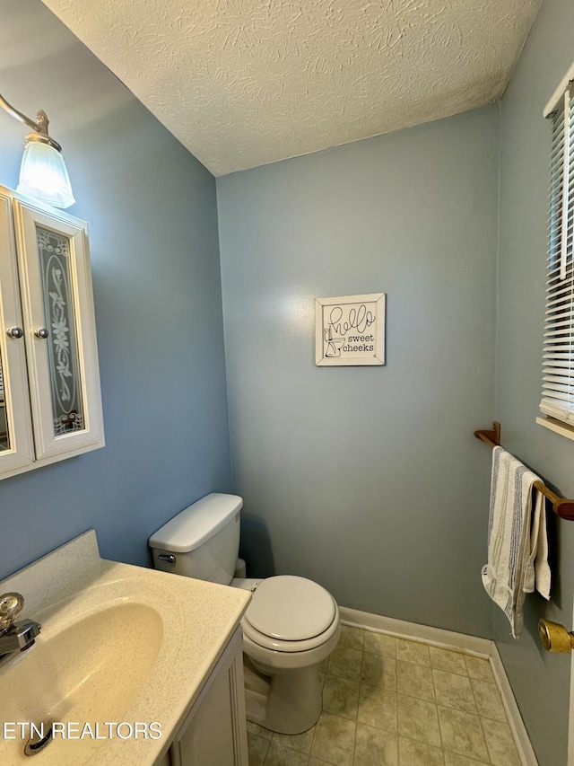 bathroom featuring toilet, baseboards, a textured ceiling, and vanity