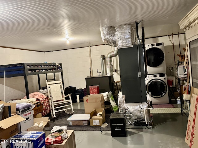 interior space with stacked washer and clothes dryer and concrete block wall