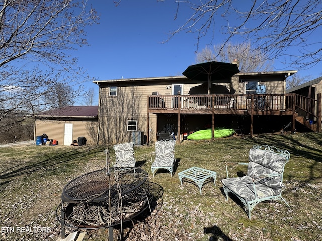 back of property with a lawn, a fire pit, and a wooden deck