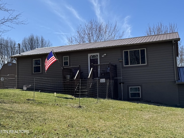 view of front of home with an outbuilding, fence, metal roof, and a front yard