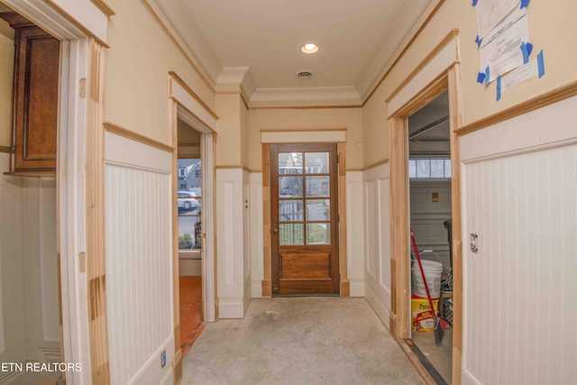 doorway featuring visible vents, a wainscoted wall, concrete flooring, crown molding, and a decorative wall