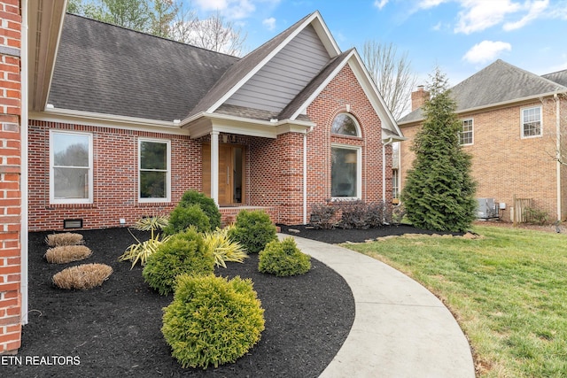 view of front of home featuring a shingled roof, brick siding, central AC, and a front lawn