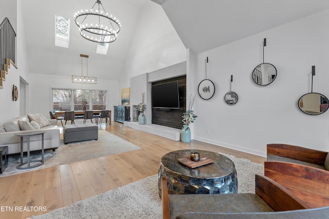 living room featuring hardwood / wood-style flooring, baseboards, high vaulted ceiling, and an inviting chandelier