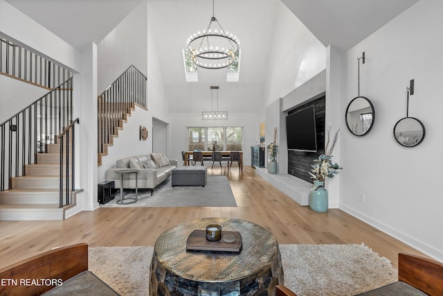 living area with baseboards, stairway, an inviting chandelier, and wood finished floors