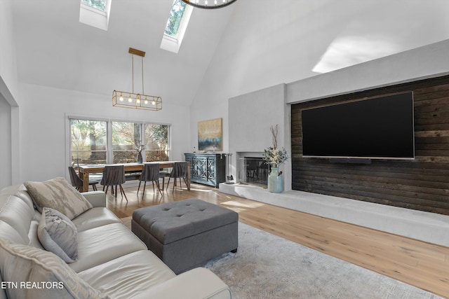 living room featuring high vaulted ceiling, a wealth of natural light, a skylight, and wood finished floors