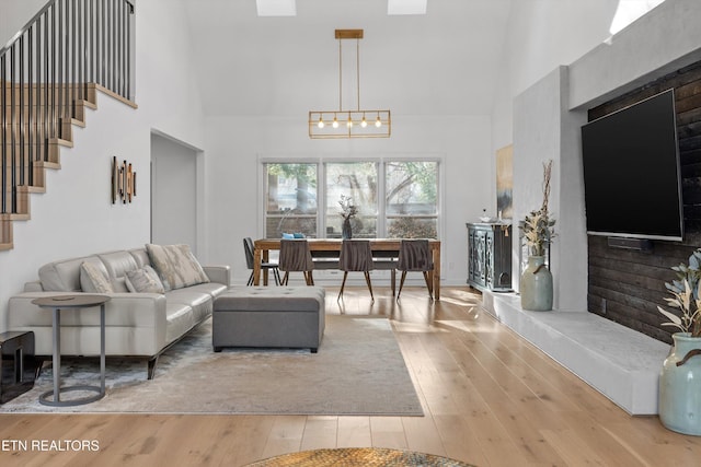 living area featuring stairway, a towering ceiling, an inviting chandelier, and hardwood / wood-style flooring