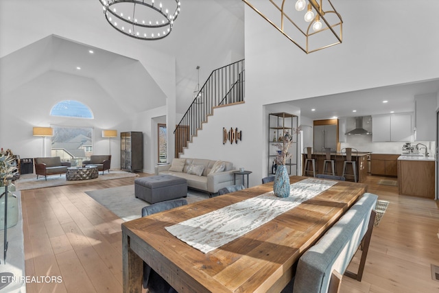 dining room featuring a chandelier, a high ceiling, light wood finished floors, and stairs