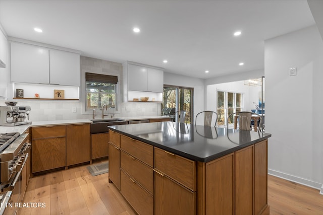 kitchen featuring a kitchen island, a sink, light wood finished floors, and open shelves