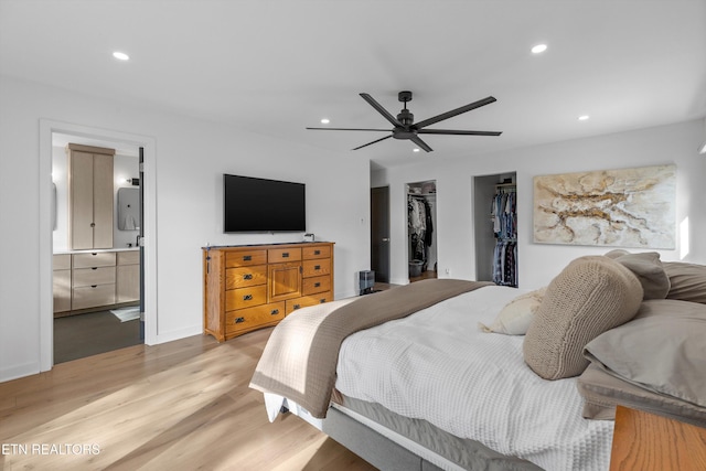 bedroom with recessed lighting, connected bathroom, a spacious closet, and light wood finished floors