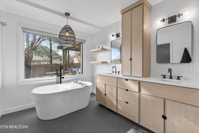 bathroom featuring double vanity, a freestanding bath, baseboards, and a sink