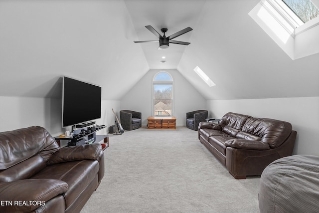 carpeted living room with vaulted ceiling with skylight and a ceiling fan