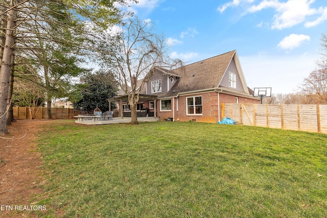 rear view of property featuring a fenced backyard, brick siding, a shingled roof, a yard, and crawl space