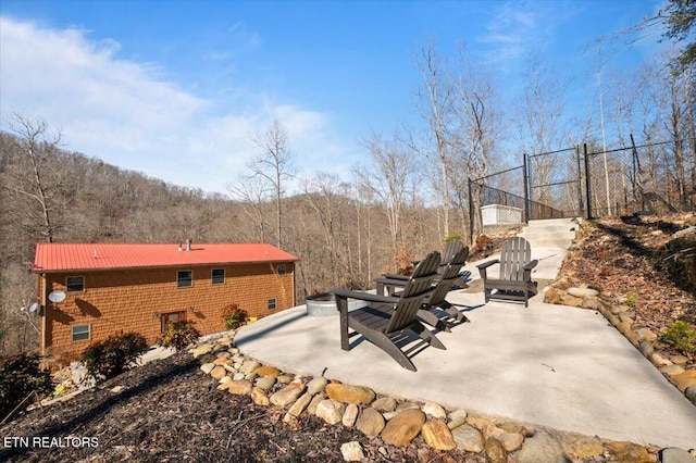 view of patio / terrace with a gate, fence, and a view of trees