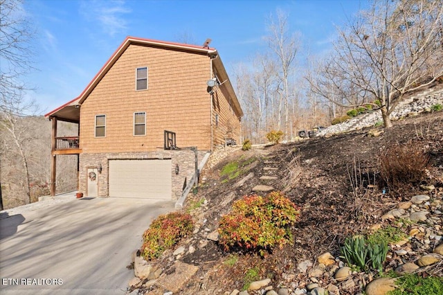 view of property exterior with an attached garage and concrete driveway