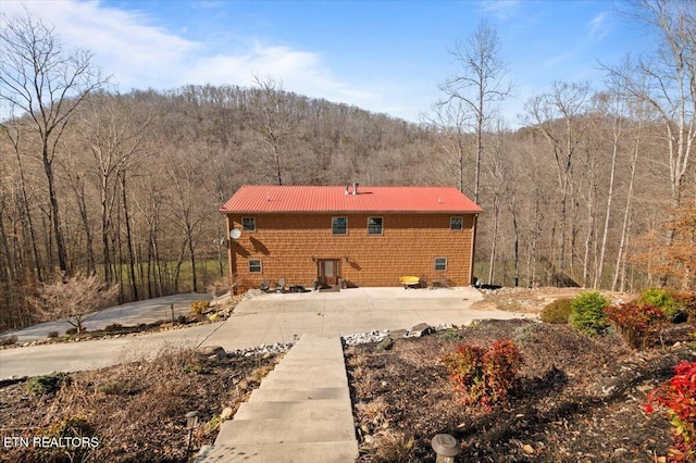 rear view of house with a forest view and metal roof