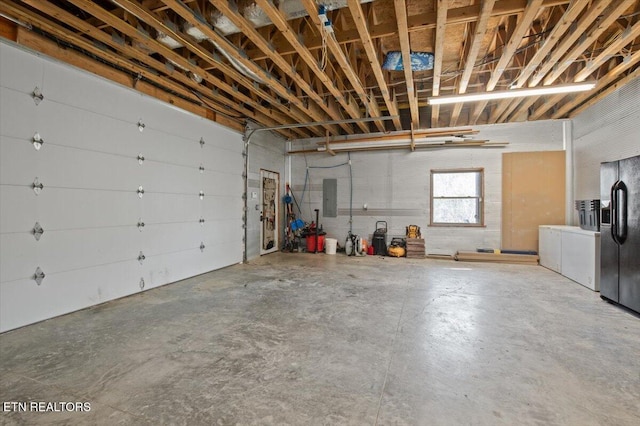 garage featuring electric panel and black refrigerator with ice dispenser