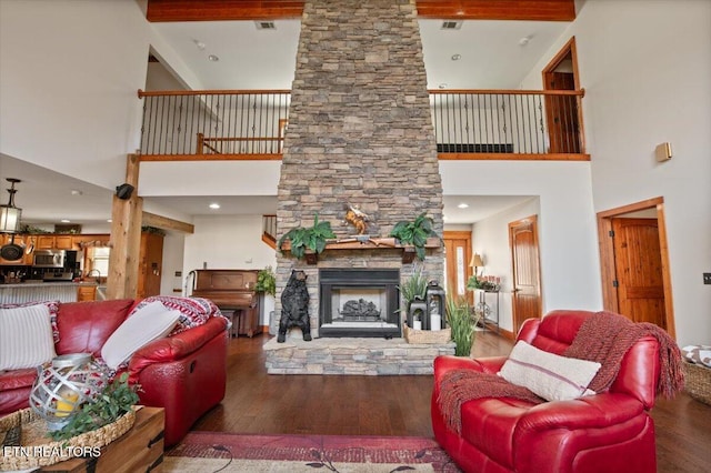 living area with a stone fireplace, wood finished floors, and visible vents