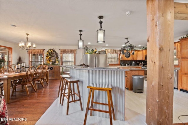 kitchen with a breakfast bar, light wood-style flooring, appliances with stainless steel finishes, a kitchen island, and a chandelier