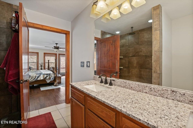 bathroom featuring ceiling fan, ensuite bathroom, tile patterned flooring, vanity, and a tile shower