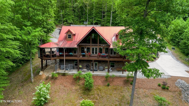 715 Landmark Rd, Jacksboro, TN 37757 - rear view of house with a patio area, a wooden deck, a forest view, metal roof, and stone siding