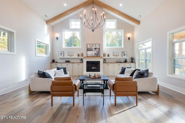 living room with light wood-type flooring, high vaulted ceiling, beam ceiling, and a glass covered fireplace