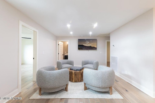 living area with baseboards, light wood-type flooring, visible vents, and recessed lighting