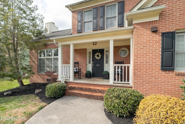 property entrance featuring brick siding and covered porch