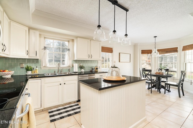 kitchen featuring light tile patterned flooring, plenty of natural light, a sink, dark countertops, and a center island