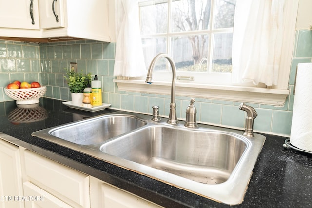 details with dark countertops, white cabinetry, tasteful backsplash, and a sink