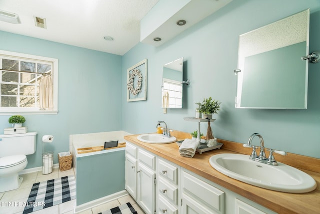 bathroom featuring tile patterned flooring, double vanity, toilet, and a sink