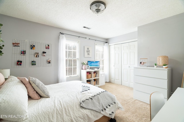 carpeted bedroom featuring visible vents, a textured ceiling, and a closet